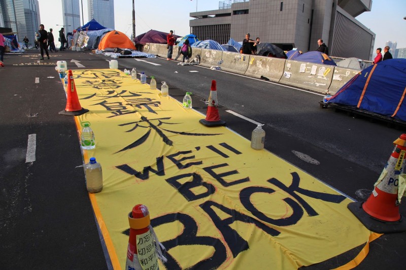 Bloger Au Ka Lun uvádí, že na místě protestů ve čtvrti Admiralty bylo více než 100 transparentů s nápisem „My se vrátíme!“ – předtím, než policie toto místo 11. prosince vyklidila. Autor fotografie Au Ka Lun, nekomerční využití.