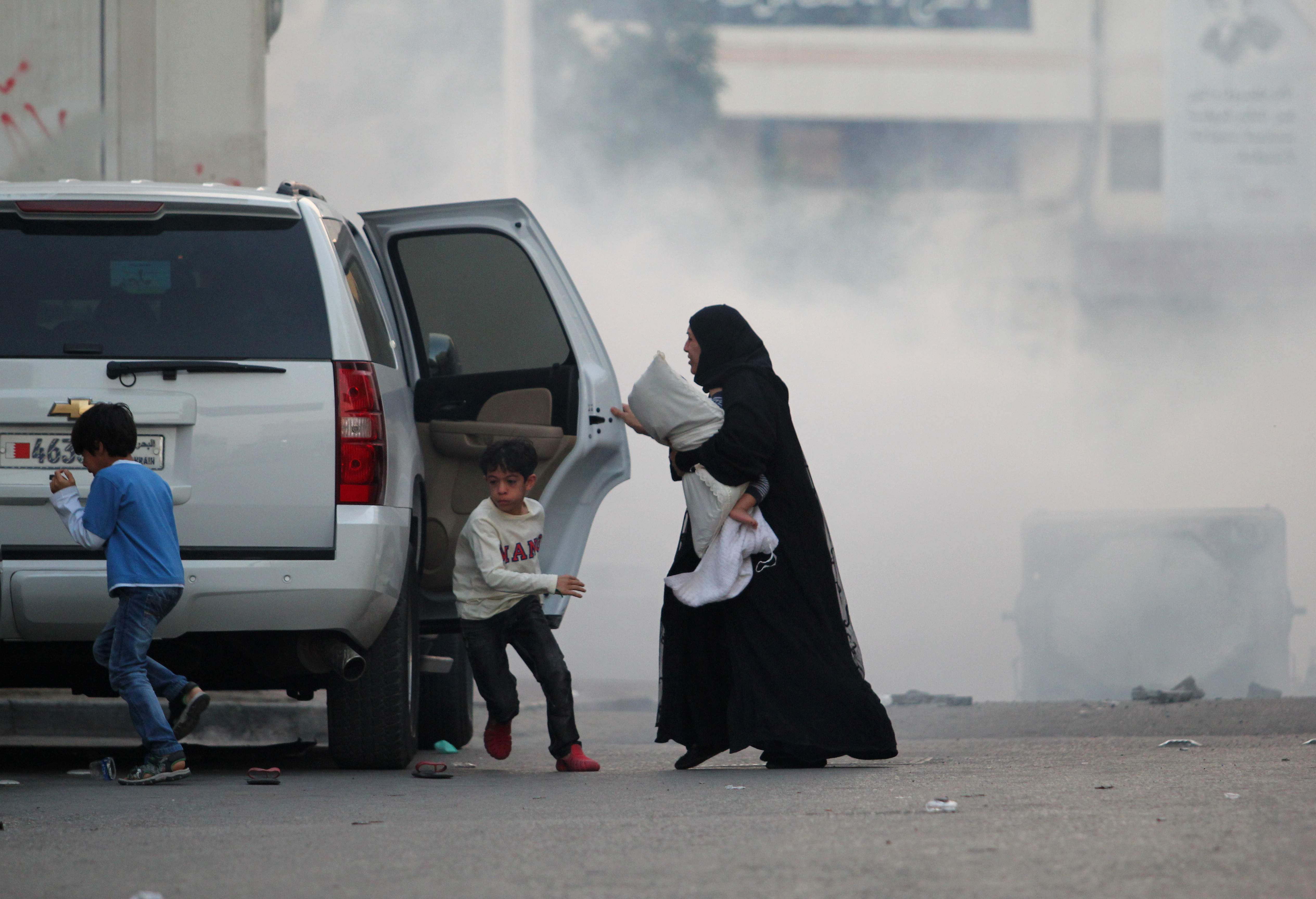 Manáma, Bahrajn, 2. ledna 2015. Holčička uprostřed slzného plynu, její matka a sourozenci spěchají uprostřed chaosu do auta. Dochází k násilným střetům mezi demonstranty a jednotkami policie poté, co byl zatčen Šejk Ali Salman. Opoziční protestující volají po jeho okamžitém propuštění. Autor fotografie Sayed Baqer Al Kamel. Copyright: Demotix