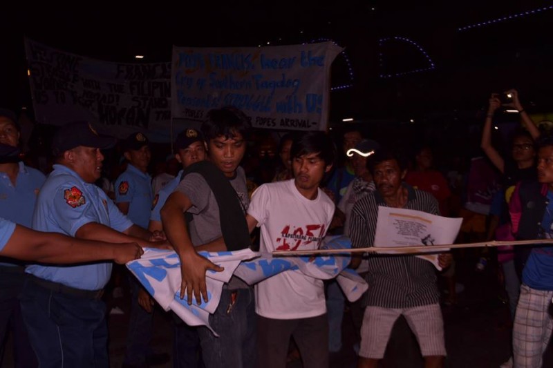 Members of the police confiscate an activist banner along the pope motorcade. Police said only "greeting streamers" are permitted. Photo from Facebook page of Southern Tagalog Exposure