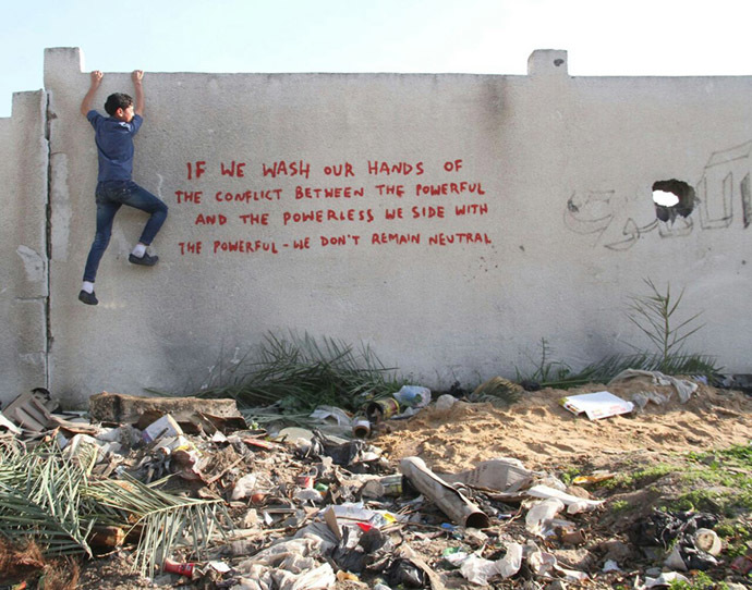 Palestinian kid climbs the wall featuring Banksy's message
