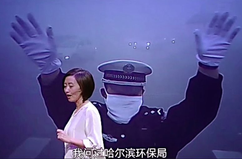 Chai addresses her audience with a picture from the smog-filled Northeastern city of Harbin in the background.