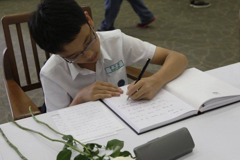 A student writes a note honoring Lee Kuan Yew