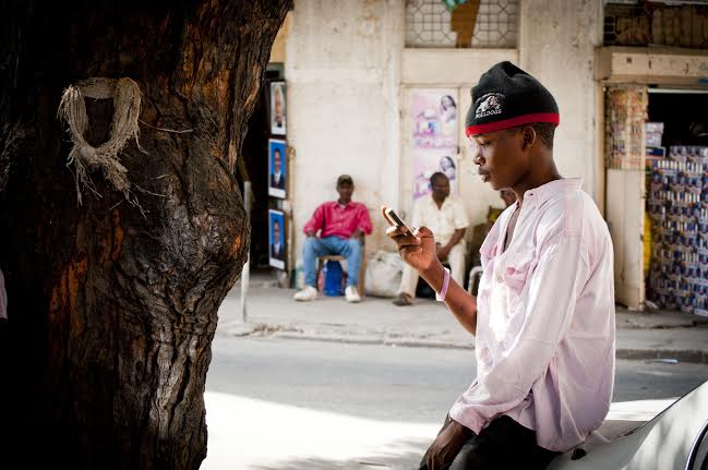 Un jeune homme envoyant des textos sur son téléphone portable à Dar Es Salaam, en Tanzanie. Photo par Pernille Baerendtsen, utilisée avec permission.