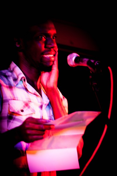 Gerry Bukini, steps on stage reciting a poem in Swahili. Blinded by the red spotlight, he tries to focus on the audience while he clicks his poem forward on his mobile phone screen. ‘I didn’t know I could write poems in my own language’ he says in a break between performances. 