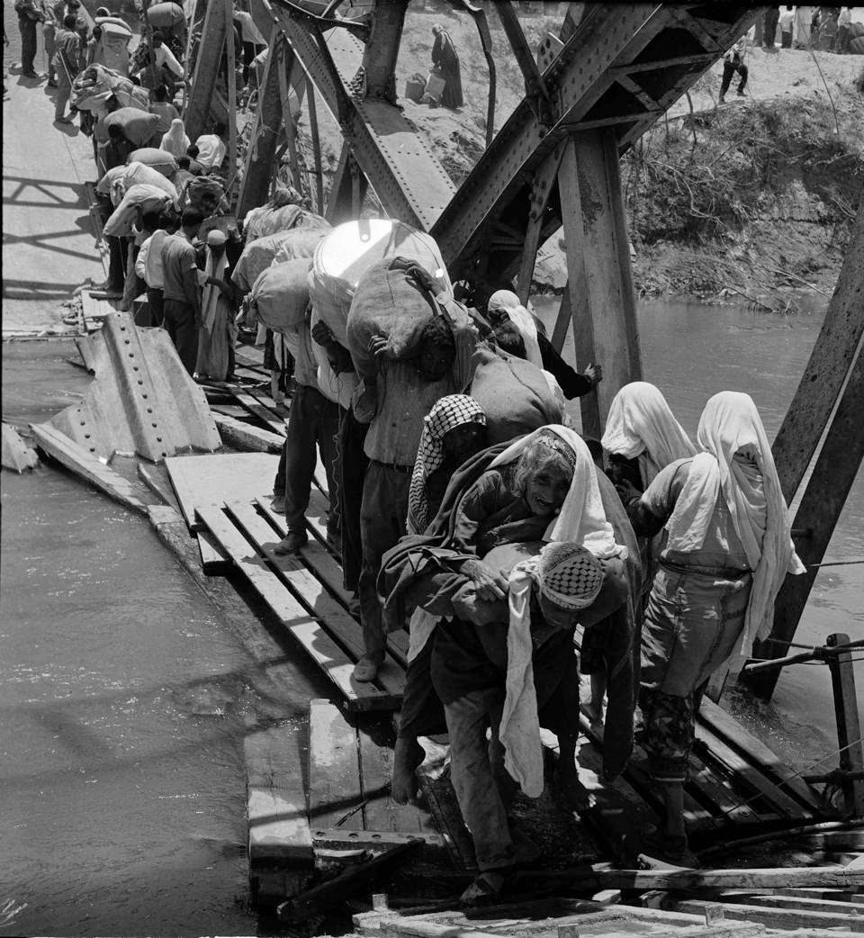 Palestine refugees flee across over the Jordan river on the damaged Allenby Bridge during the 1967 Arab-Israeli war. (UNRWA archives)