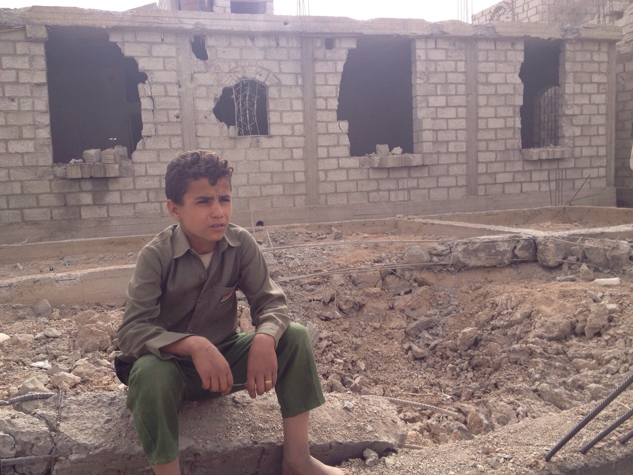 A young boy, who was luckily in school during the aerial attack by Saudi-led forces, sits outside his home on debris.r, 90KM south of Sanaa the capital of Yemen, in the afternoon hours on Tuesday, April 14, 2015.