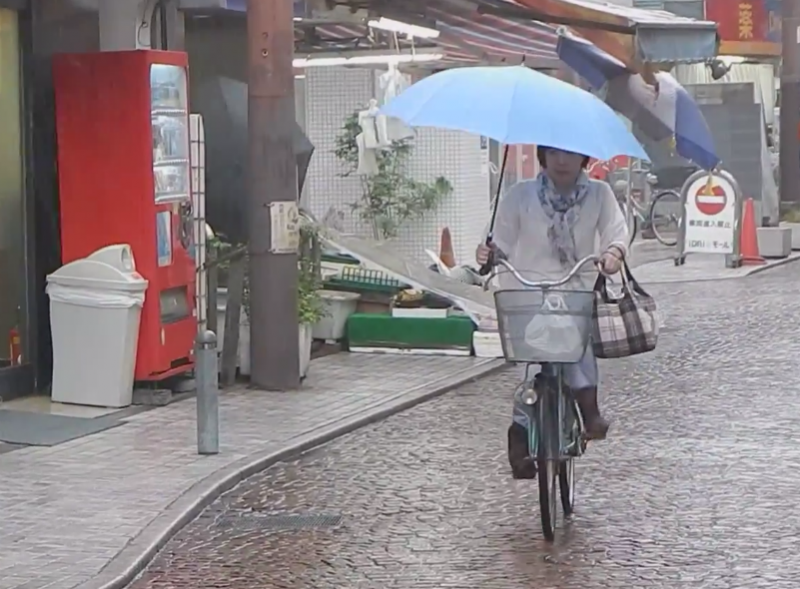 Under the new regulations, bicyclists can no longer use smartphones while riding, but may still use umbrellas. Screencap from YouTube user XXX.