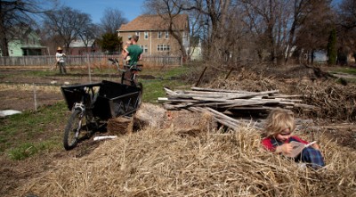 In addition to raising vegetables, urban gardens can help families raise kids who enjoy the outdoors. Photo of Rising Pheasant Farms’ Carolyn Leadley and family by Marcin Szczepanski. Used with permission of the photographer.