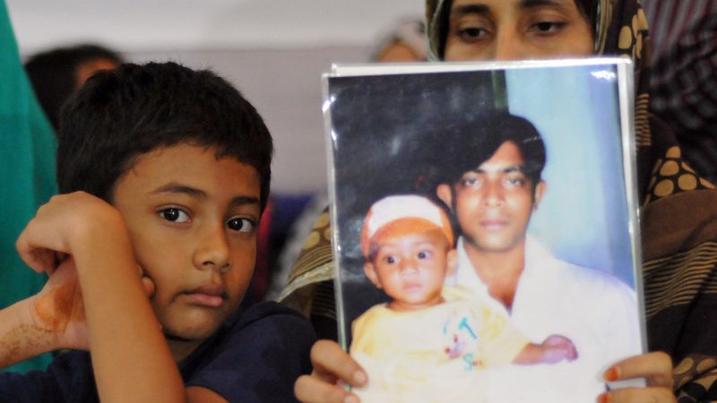 A relative holding up a portrait of the disappeared person. Image by Indrajit Ghosh. Copyright: Demotix (30/08/2014)
