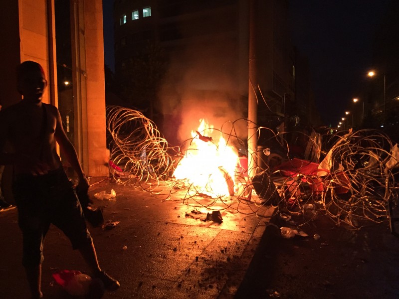 Beirut, Lebanon. 23rd August 2015 -- A man stands next to burning barb-wire in Riad el Solh Square in Beirut, Lebanon after the army was deployed to curb the rubbish disposal protesters rallying in the capital against the government. -- Protest organized by the "You Stink" movement Sunday turned into violence in Beirut Riad AlSolh square after protesters started to remove the barbed wire that leads to the Grand Seraii, Lebanese government head quarters building. Photograph by Issam Abdallah. Copyright: Demotix
