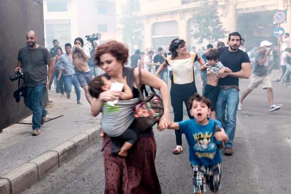 أم وأطفالها يهربون من القنابل المسيلة للدموع الموجهة الى المتظاهرين من قبل الشرطة في بيروت.