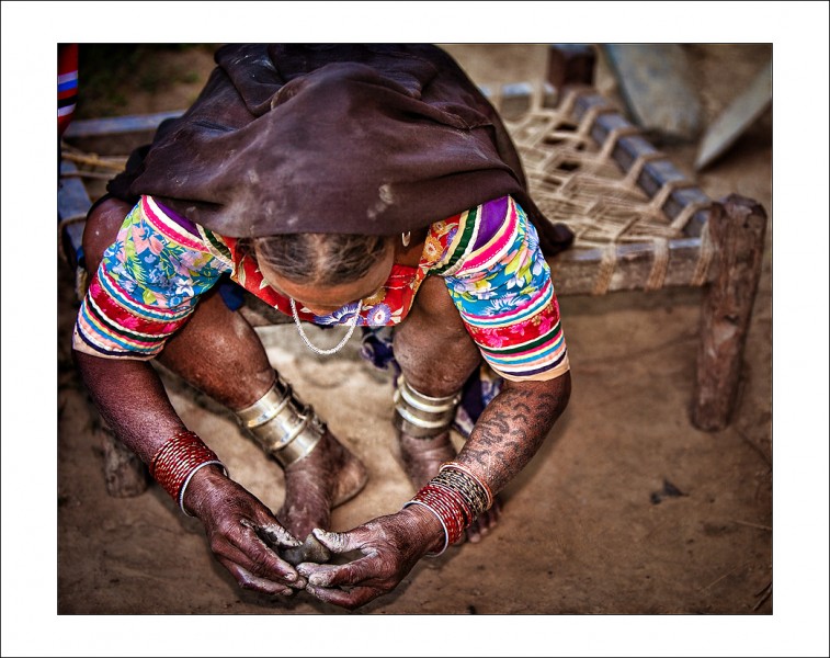 The lady in her bright blouse sits on a rope cot and makes clay figurines for her grandchildren to play with in the upcoming festival. She draws inspiration from the nature, the tattoos on her arms and the bright colours of her blouse. 